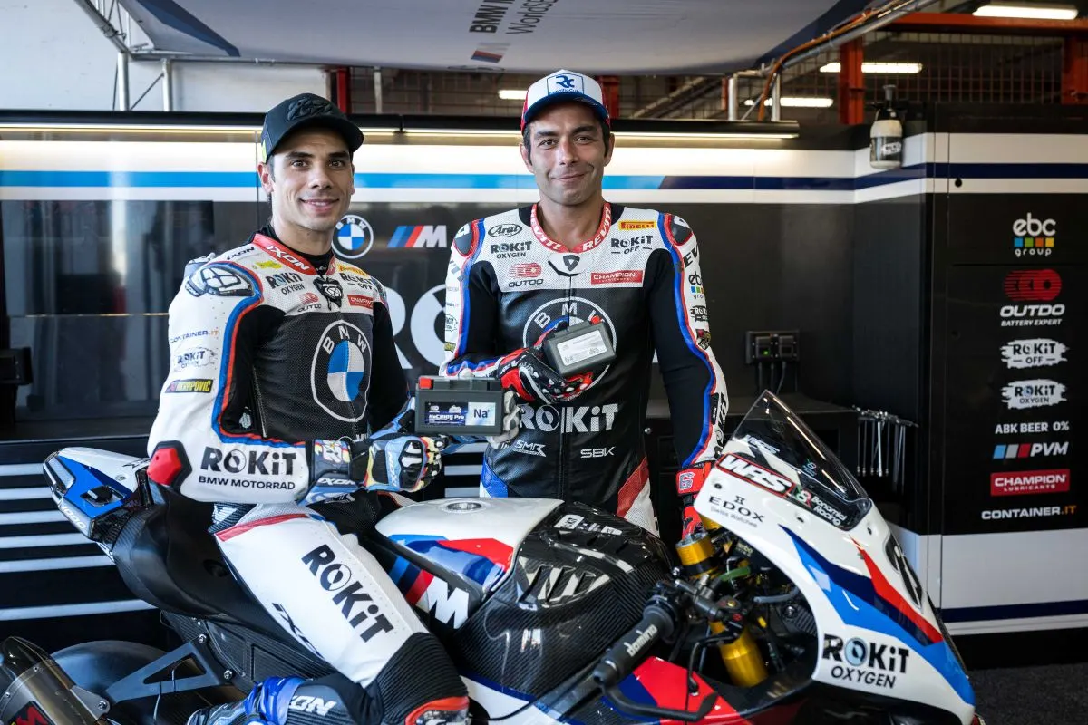 BMW Motorrad WorldSBK Team riders holding OUTDO sodium-ion motorcycle batteries in the team garage