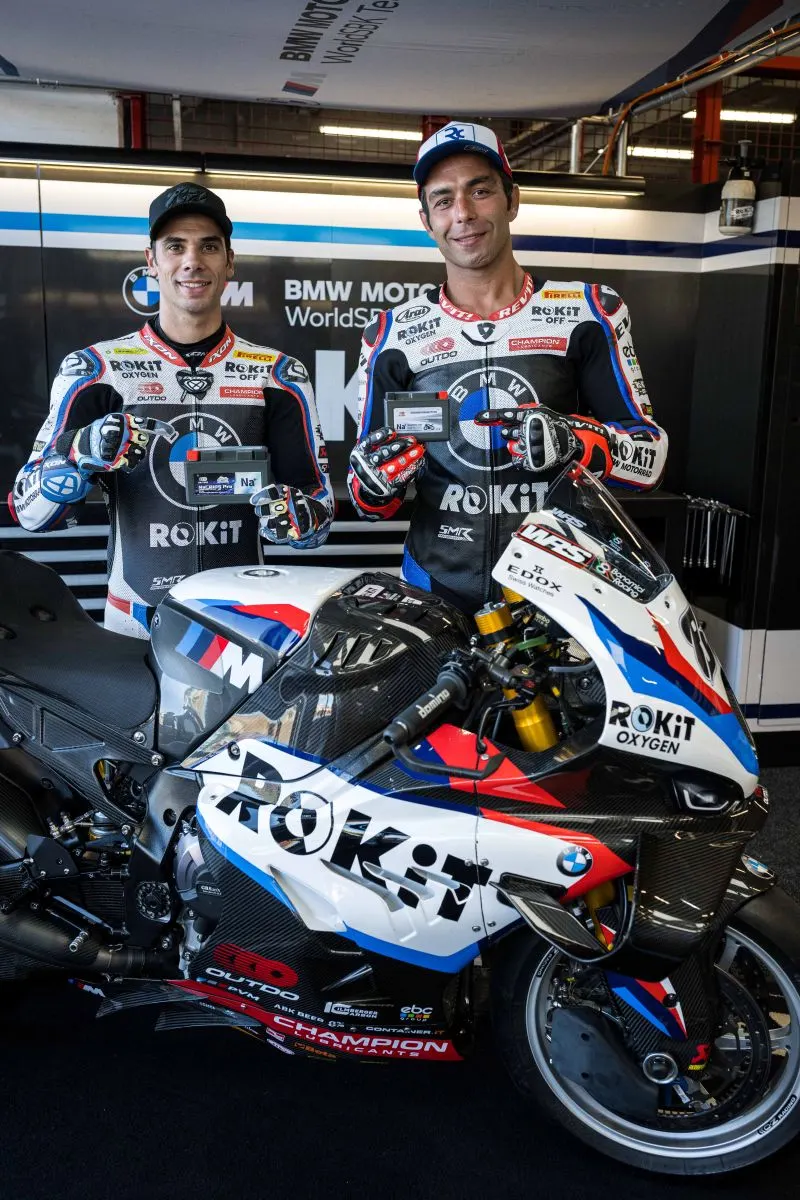 BMW Motorrad WorldSBK Team riders standing behind the ROKiT race bike holding OUTDO sodium-ion batteries