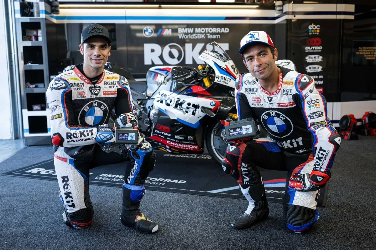 BMW Motorrad WorldSBK Team riders kneeling with OUTDO sodium-ion batteries in front of the team race bike