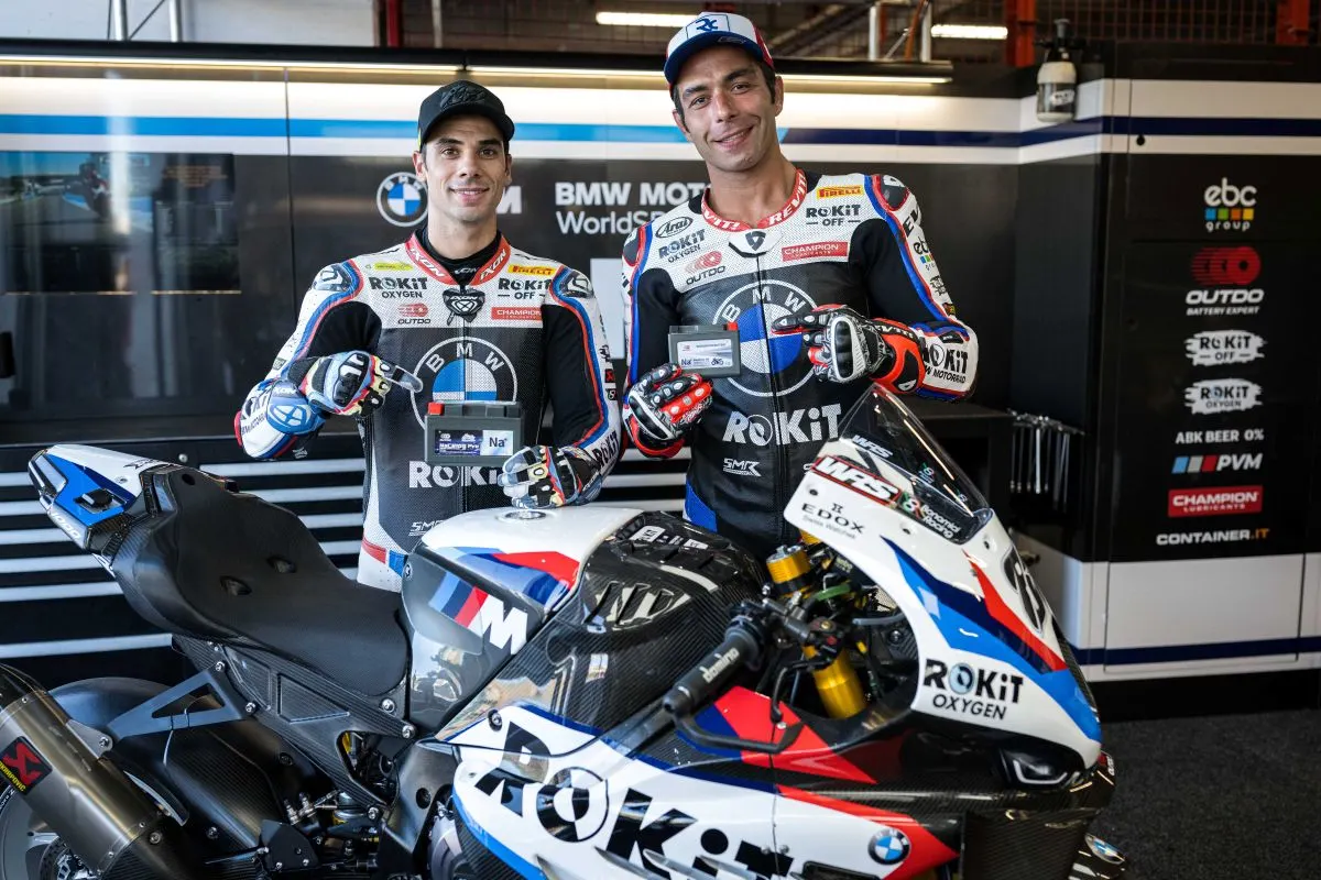 BMW Motorrad WorldSBK Team riders smiling with OUTDO sodium-ion batteries behind the ROKiT race bike